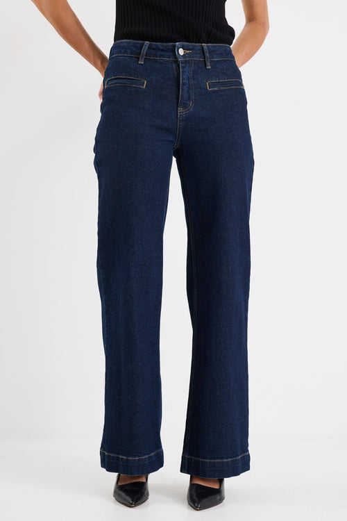 Person wearing dark blue jeans and a black top on a white background