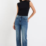 Woman wearing a black sleeveless top and blue jeans on a white background