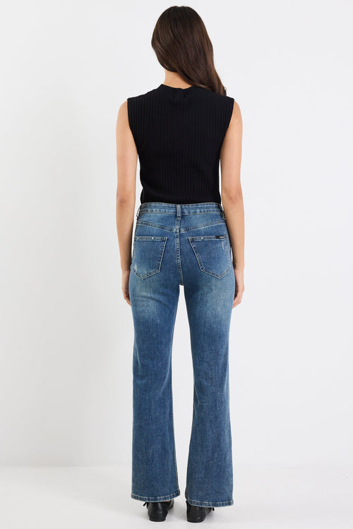 Person wearing blue jeans and a black sleeveless top on a white background