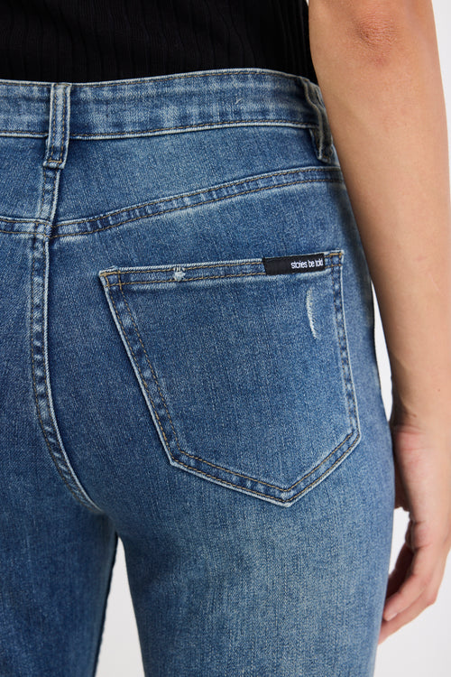 Close-up of blue jeans with a brand label on the pocket against a white background