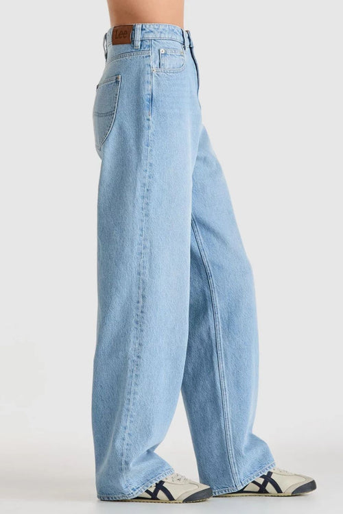 light blue high-rise wide leg jeans with patch pockets and leather logo patch on waistband. Model wears them full length with relaxed fit through the legs.