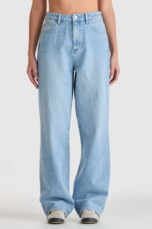 light blue high-rise wide leg jeans with patch pockets and leather logo patch on waistband. Model wears them full length with relaxed fit through the legs.