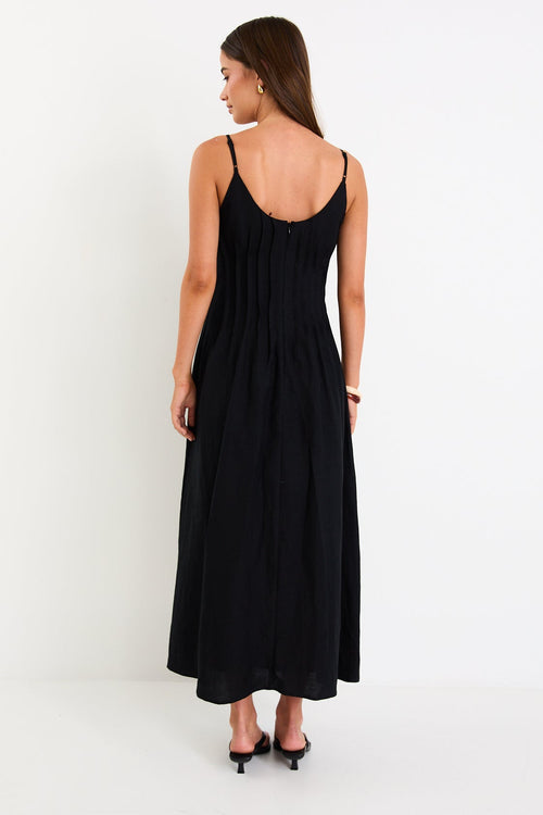Model wearing a black strappy linen-blend maxi dress with a pleated bodice and an A-line flowing skirt.