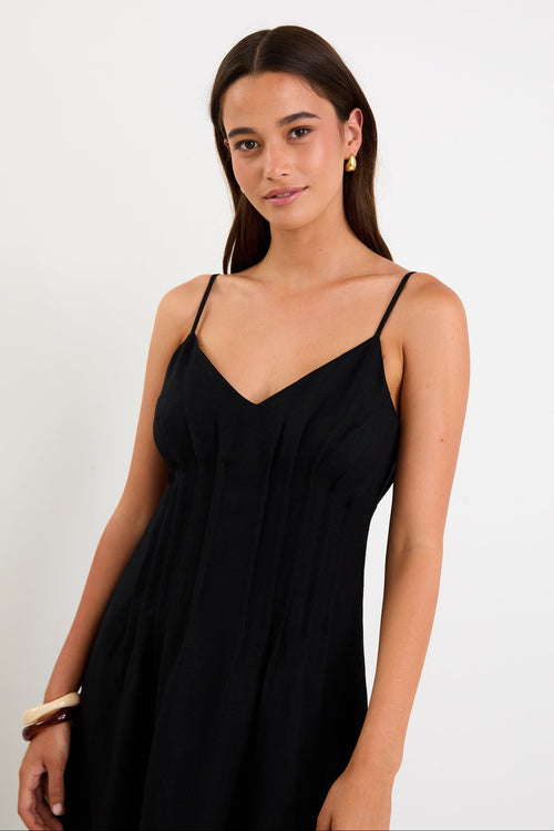 Model wearing a black strappy linen-blend maxi dress with a pleated bodice and an A-line flowing skirt.