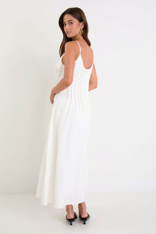 Woman wearing a white dress with thin straps on a plain background