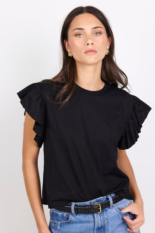 Woman wearing a black top with ruffled sleeves against a white background