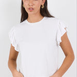 Woman wearing a white ruffled top and dark jeans on a white background
