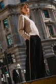 Woman standing on a street corner with a large building in the background