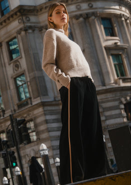 Woman standing on a street corner with a large building in the background