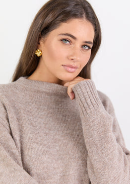 Woman wearing a beige sweater against a white background