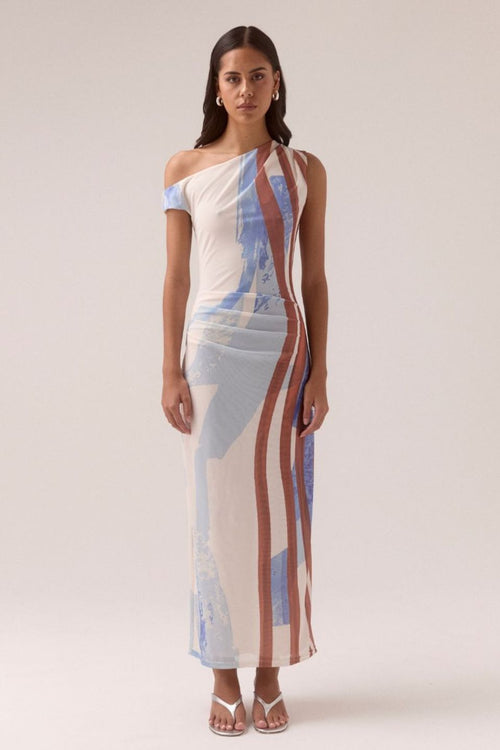 One-shoulder mesh maxi dress with vertical abstract stripes in blue, rust, and cream tones, featuring a fitted silhouette and side ruching, worn by a model in white sandals against a neutral background.