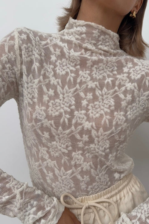 Model wears a cream lace long sleeve high neck top