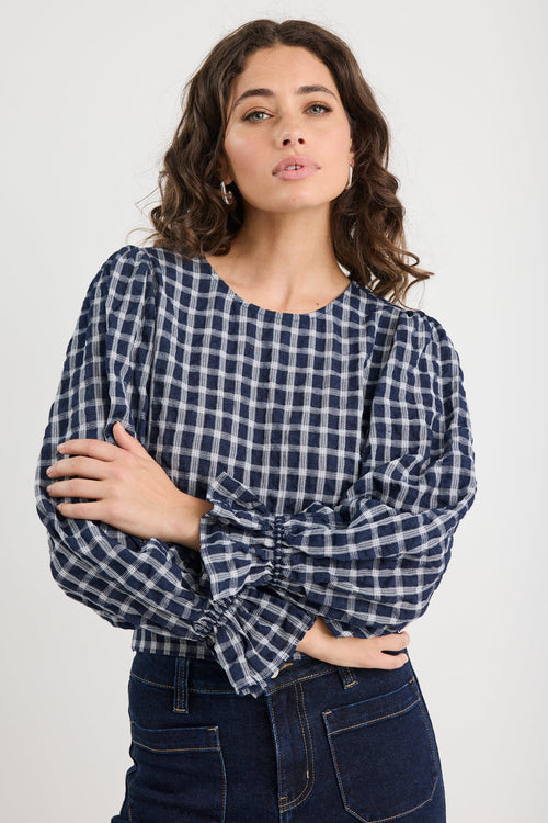 Woman wearing a blue and white checkered blouse against a plain background
