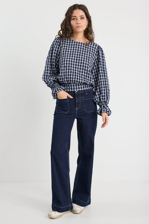 Woman wearing a checkered shirt and dark blue jeans on a white background
