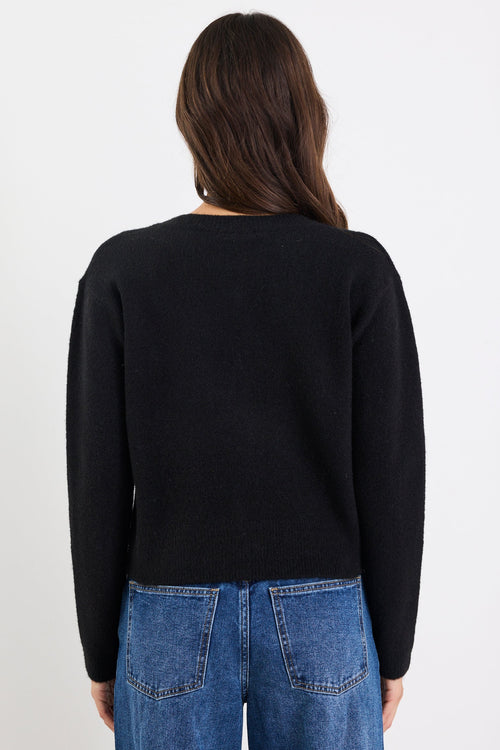 Person wearing a black sweater and blue jeans on a white background