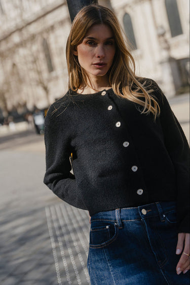 Woman wearing a black cardigan with white buttons in an urban setting