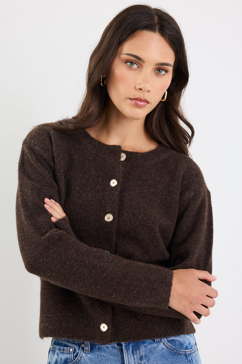 Woman wearing a brown cardigan with button details on a white background