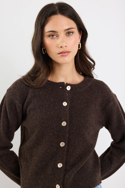Woman wearing a brown cardigan with a plain background