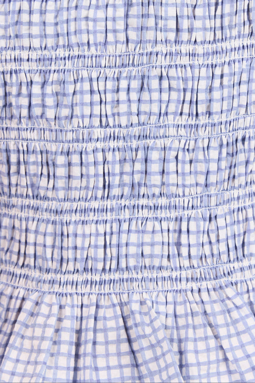 Close-up of a smocked gingham fabric with horizontal gathered seams in a light blue and white checkered pattern.