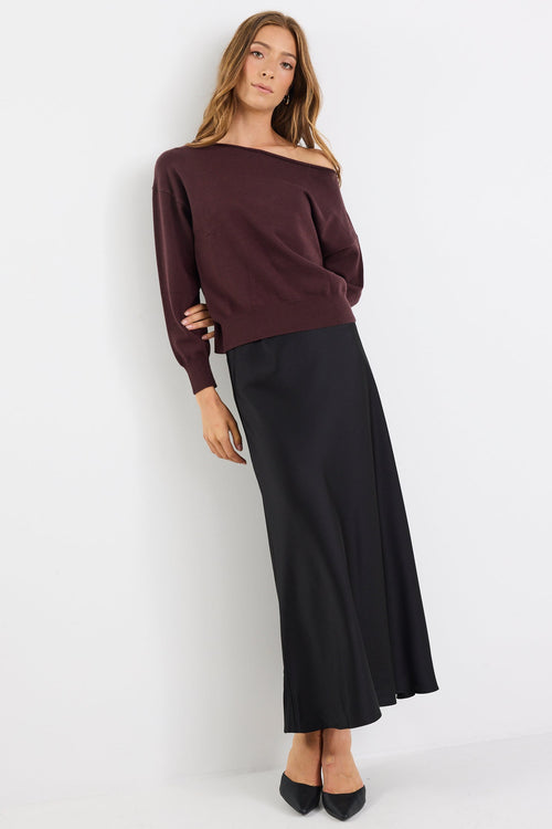Woman wearing a brown off-shoulder top and black skirt on a white background