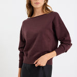 Woman wearing a dark purple sweater against a white background