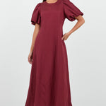 Woman wearing a burgundy dress with puff sleeves on a white background