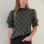 Model wears a black check top with black jeans