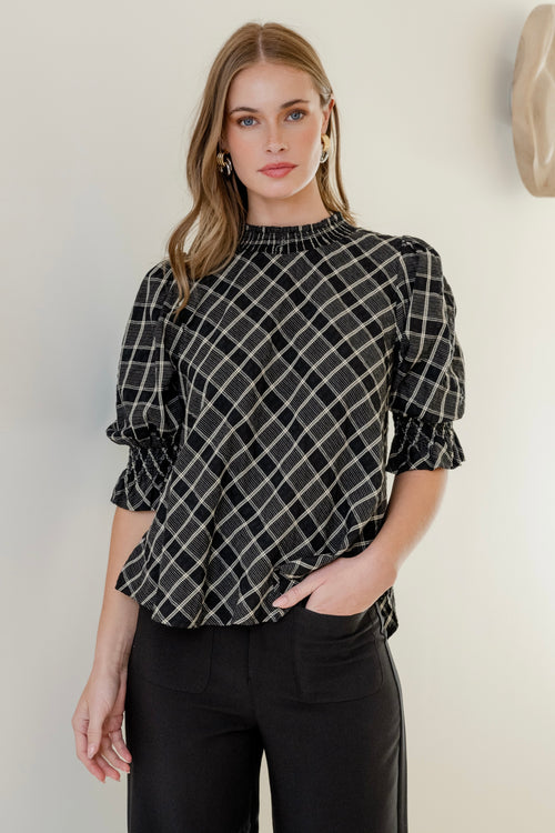 Model wears a black check top with black jeans