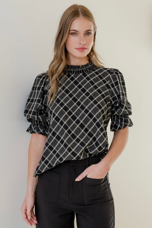 Model wears a black check top with black jeans