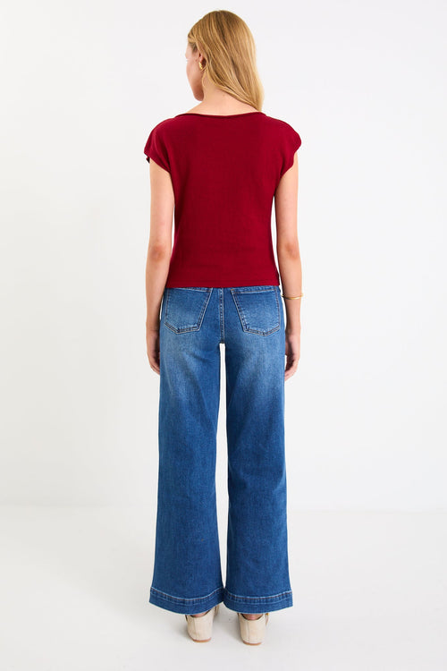 Model wearing a cherry red sleeveless knit top with a boatneck neckline