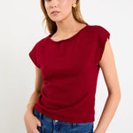 Model wearing a cherry red sleeveless knit top with a boatneck neckline