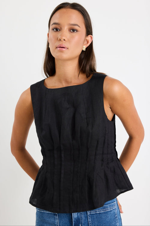 Woman wearing a black pintuck top with blue jeans