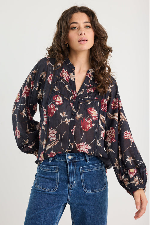Woman wearing a floral blouse and blue jeans on a white background