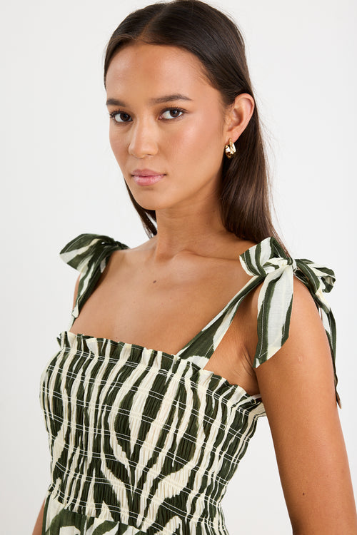 Model wearing a bold khaki zebra print dress with strappy tie details, a shirred bodice, and a tiered design. 