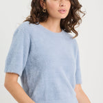 Woman wearing a light blue sweater and jeans on a white background