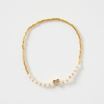 Ivory and gold beaded bracelet with a small heart charm, featuring gold cube beads and ivory accents. Delicate women’s jewellery perfect for gifting or stacking, photographed on a clean white background