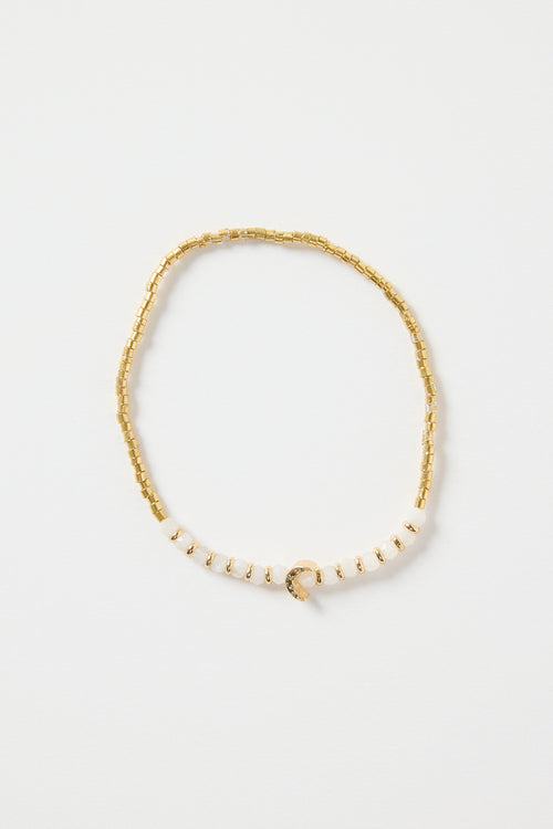 Gold and ivory beaded bracelet with a small gold heart charm in the centre, photographed on a clean white background.