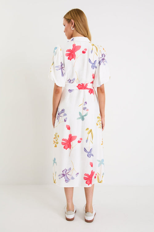 Model wearing a cream midi shirt dress with colourful poppy floral print, puff sleeves and a waist tie.