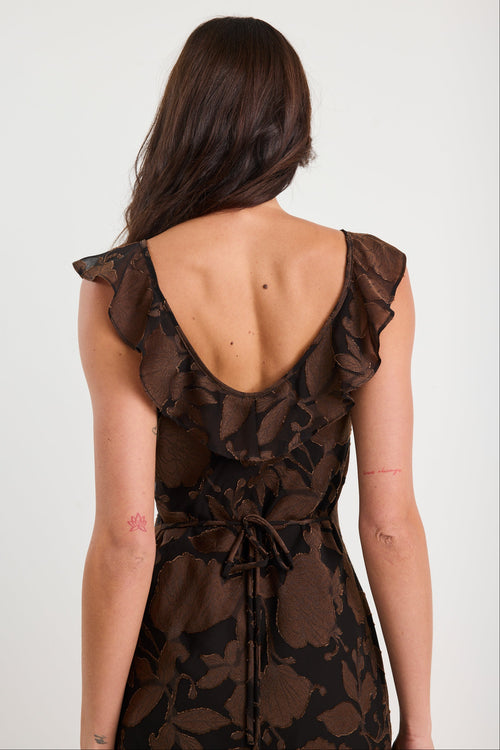 Woman wearing a brown floral dress with ruffled sleeves on a white background