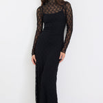 Woman wearing a black dress with lace sleeves on a white background