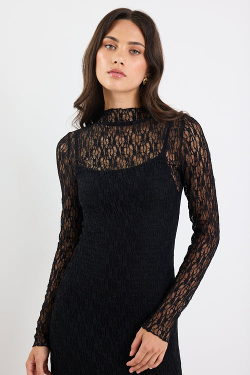 Woman wearing a black lace dress against a white background