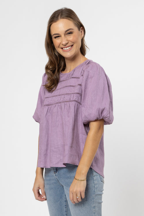 model wears a purple top with jeans