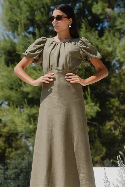 Woman wearing a green dress with puff sleeves against a natural background