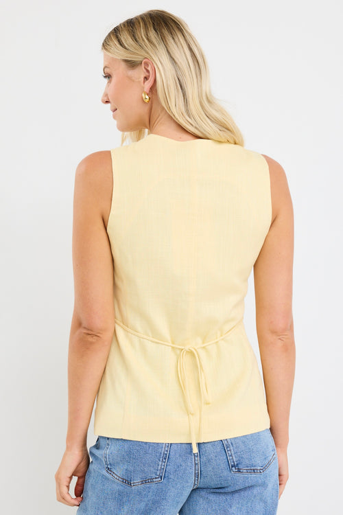 model wears a yellow linen vest with light blue jeans