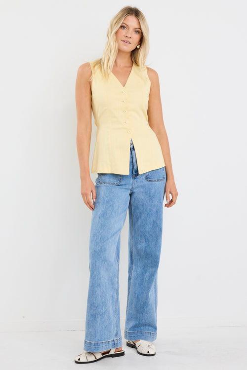 model wears a yellow linen vest with light blue jeans