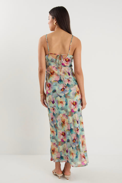 model wears a blue floral maxi dress with white heels