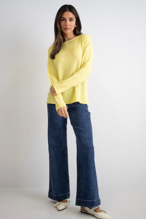 model wears a yellow knit with dark blue jeans