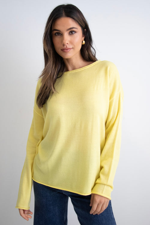 model wears a yellow knit with dark blue jeans