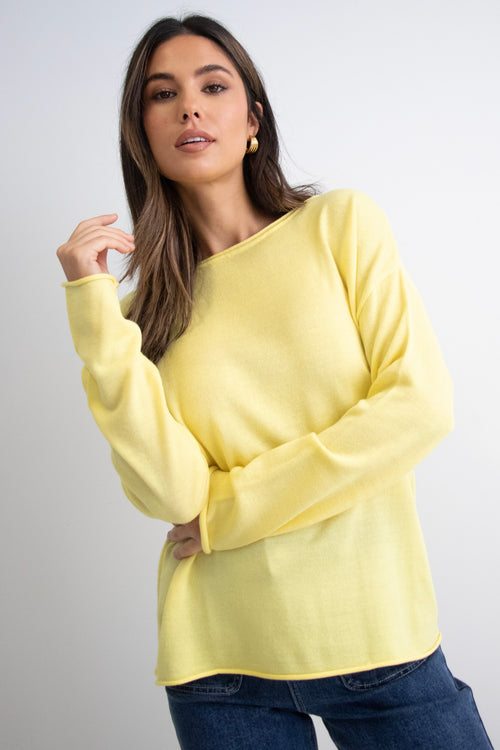 model wears a yellow knit with dark blue jeans