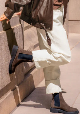 Person wearing brown boots and a leather jacket on a staircase.